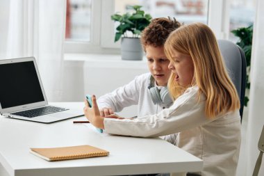 Mutlu Kafkasyalı erkek ve kız evlerinde ders çalışıyor, bilgisayar ve kulaklıkla online 11 dolar kazanıyorlar rahat oturma odalarında bir masada oturuyorlar, derslerine yoğunlaşıyorlar.