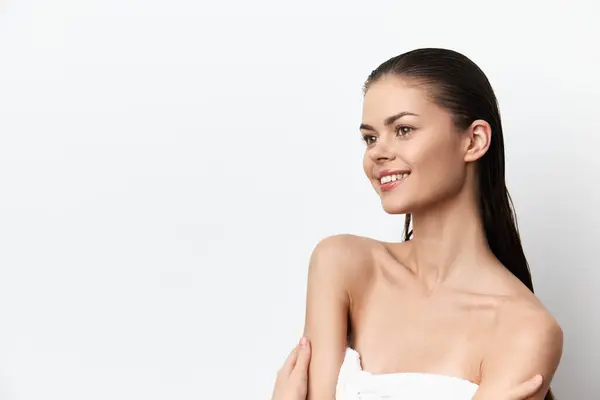 stock image portrait of a smiling woman with long, wet hair against a clean white background Emphasizing natural beauty and confidence, this image is perfect for beauty and wellness promotion