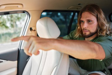 Genç bir adam arabanın yolcu koltuğundan el kol hareketi yapar. Bu da dışarıdaki şeyin açık renkli olduğunu ve sıcak bir atmosfer yarattığını gösterir.