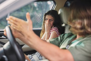 Aracın içinde gergin bir an yüzünü elleriyle kapatan bir kadın ve hayal kırıklığını ifade eden bir erkek kalabalık ve duygusal bir ortam yakalar.