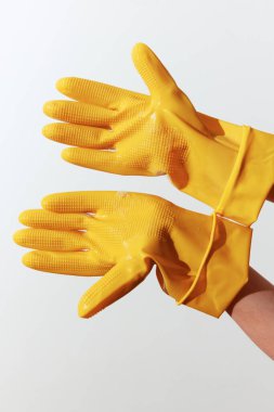 Sarı temizlik eldivenleri beyaz arka planda bir kadının elleri tarafından tutuluyor. ev temizliği ve hijyen kavramı..