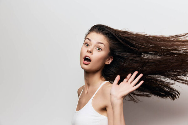 surprised woman with long hair in motion, displaying an expressive face and dynamic pose against a light background The image highlights youthfulness and spontaneity
