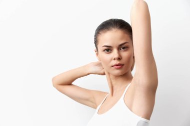 İpeksi tenli kendine güvenen bir kadın zarif bir şekilde beyaz bir arkaplana karşı poz verir. İfadesi güzellik ve duruş yayar. Bu görüntüyü güzellik, moda ve sağlık projeleri için ideal kılar.