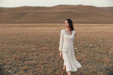 Beyaz elbiseli kadın çayırlarda yürüyor çöl manzarasında seyahat macerası sırasında