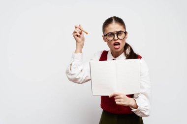 Öğrenci, eğitim, sınıf sahnesi, gözlüklü ciddi bir kız elinde boş bir defter, fikirlerini coşkuyla ifade eden beyaz arka plan öğrenme ve yaratıcılığa odaklanıyor.