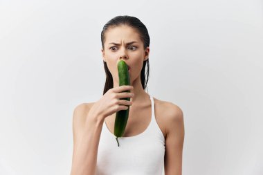 Elinde salatalık olan bir kadın beyaz arka planda seks oyuncağı taklidi yapıyor. Yüksek kalite fotoğraf