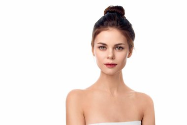 Havlu giymiş bir kadın, elleri kalçasında ve kafasında havluyla poz veriyor, beyaz arka planda soyutlanmış..