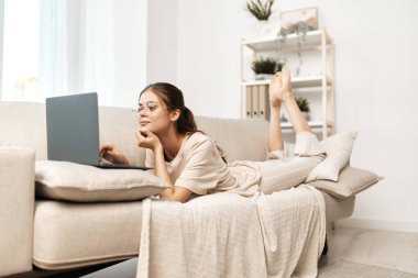 Dizüstü bilgisayarda gülümseyen kadın, Evdeki Modern Serbest Yaşam tarzının tadını çıkarıyor.