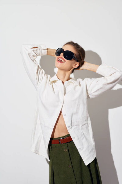 Стильная модель носит свободную белую рубашку и оливковую зеленую юбку, излучая веселое поведение.