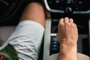 A man s hand gripping the gear shift in a stylish car cockpit, showcasing sleek design and modern features clipart