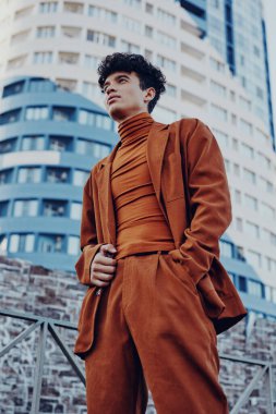 Kahverengi takım elbiseli şık bir genç adam modern mimarinin önünde duruyor.