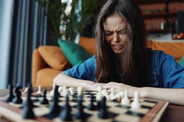 Oturma odasındaki rahat kanepenin önünde satranç oynayan kadın.