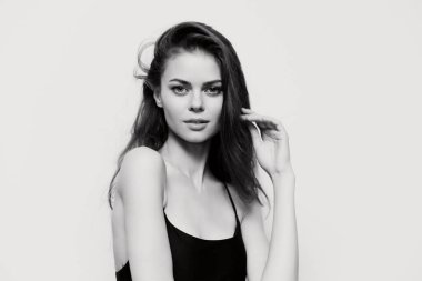 Zarif bir kadının portresi kendine güveni ve dalgalı saçlarıyla yumuşak beyaz arka planda duruşu. Güzellik ve moda temaları için ideal.