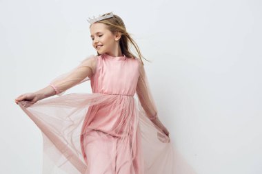 Taçlı pembe tüllü neşeli genç kız, garip bir ortamda zarif bir şekilde dans ediyor, çocukların moda tasvirleri ve duygusal anlatımları için mükemmel.