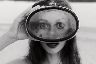 Büyük bir bardak tutan, geniş gözlü ve koyu dudaklı bir kadının çarpıcı siyah beyaz görüntüsü bulanık arka plan gizem katıyor.