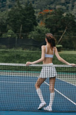 Sahada formda bir genç kadın ve tenis eteği, enerjiyi somutlaştıran spor ve forma olan aşkı, sağlıklı bir yaşam tarzını desteklemek için ideal.