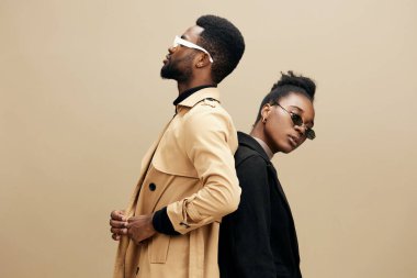 Tarafsız renklerde şık kıyafetler giyen şık bir çift kendilerine güvenen pozları, güneş gözlükleri ve modaya uygun modern zarafeti yansıtıyor.