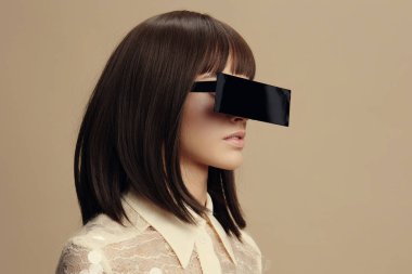 Siyah gözlüklü kadın, at kuyruklu saçlı, beyaz bluzlu.