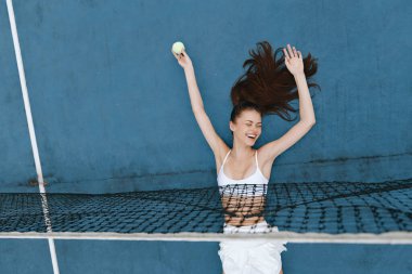 Tenis kortunda zaferini ifade eden mutlu bayan atlet, şık bir beyaz elbise giyiyor, parlak mavi bir geçmişi var, spor ve fitness promosyonları için ideal.