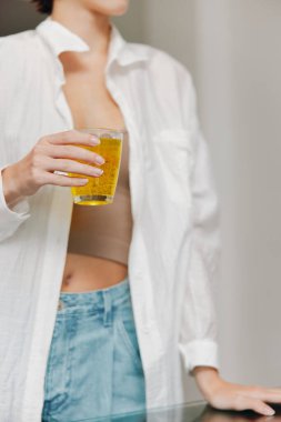Beyaz gömlekli kadın elinde bir bardak portakal suyu ve elinde bir fincan kahve tutuyor..