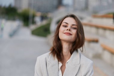 Kendine güvenen bir iş kadını şık ama rahat bir şekilde dışarıda bir andan zevk alıyor. Etrafı modern kentsel zemin ile çevrili, pozitiflik ve profesyonellik yayıyor..