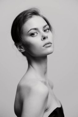 Gösterişli bakışları olan şık bir kadın minimalist siyah beyaz bir portrede sofistike bir görünüm sergiliyor. Moda ve zarafete odaklanma.