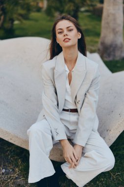 Hafif takım elbiseli kendine güvenen bir iş kadını açık havada profesyonelliğini sergiliyor. Huzurlu arka plan onun zarif tavrını artırıyor, işle ilgili konular için ideal..