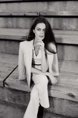 Kendine güvenen bir iş kadını terzi kıyafeti giymiş, profesyonellik ve stilin bir karışımını sergiliyor, gösterişli bir şehir ortamında yakalandı..