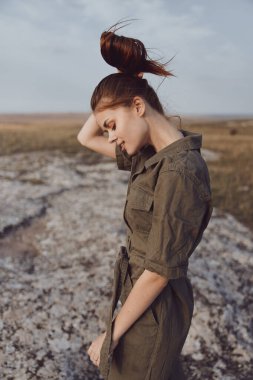 Yalnız güzel bir kadın, çörekte saçları olan çöl kayaları üzerinde duran seyahatin doğasını yansıtan.