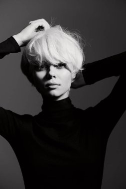 Beyaz saçlı şık bir bayan model, tek renkli arka plana karşı özgüven ve zarafet gösteriyor. Moda ve güzellik temaları için ideal.