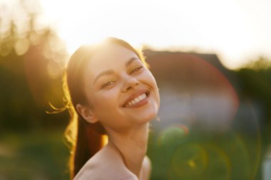 Işıl ışıl genç bir kadın, altın saat ışığında mutluluk saçıyor, açık hava ortamında geçiyor refah, pozitiflik ve yaşam tarzı kavramları için ideal.