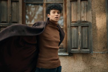 Moda adamı kahverengi balıkçı yaka ceket Eski bina ahşap panjurlar ayakta