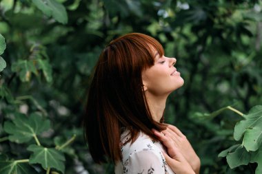 Kolları havada, yemyeşil bir yerde kutlama yapan neşeli bir kadın.