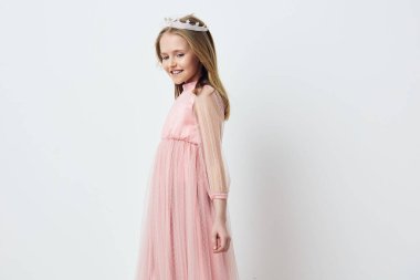 Pembe tül elbise ve taç giymiş mutlu bir genç kız. Parlak, minimalist bir ortamda masumiyet ve neşe saçıyor. Doğum günleri ve kutlamalar için mükemmel.