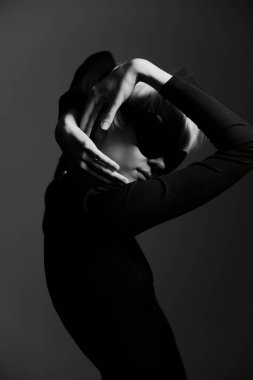 Siyahlar ve beyazlar içinde yakalanmış şık kıyafetli yaratıcı bir kadın tasviri. Görüntü sanatsal duruşunu ve güçlü duygularını vurguluyor. Moda, sanat ve güzellik birleşimi.