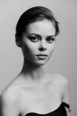 Zarif, siyah beyaz bir kadın portresi pürüzsüz bir ten ve tanımlanmış elmacık kemikleri, duruşunu ve iç gücünü yansıtıyor..