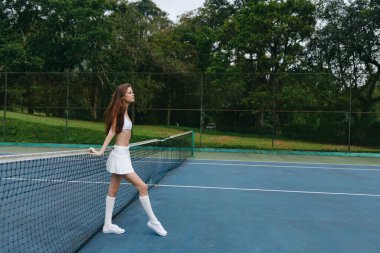 Kendine güvenen genç bayan tenisçi canlı bir tenis kortunun üzerinde duruyor, yemyeşil, enerji ve azim dolu dinamik bir spor konseptinde.