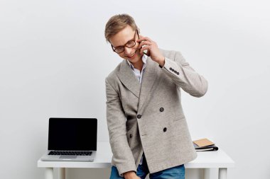 İş yerinde telefon görüşmesi yapan, açık dizüstü bilgisayarlı, not defterli, neşeli ifadeli, modern ofis ortamında minimalist