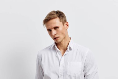 Kısa saçlı, açık tenli, beyaz gömlekli, hafif bir eğim ile poz veren, ciddi bir ifadeyle kameraya bakan şık bir genç. Geçmişi sade ve tarafsız.