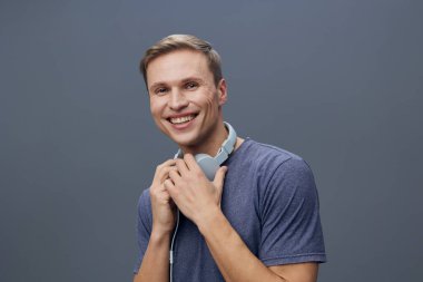 Gülümseyen bir adamın portresi, genç bir yetişkin, günlük tişörtler ve kulaklıklar giyiyor, stüdyo ortamında arkadaşça ve neşeli tavırlar sergiliyor. Konsept: mutluluk ve rahatlama