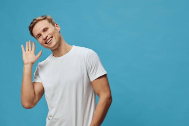 gülümseyen beyaz adam el sallıyor mavi arka planda beyaz tişört giyiyor mutlu bir jest gösteriyor olumlu duygu, dijital detoks ve zihinsel sağlık konsepti