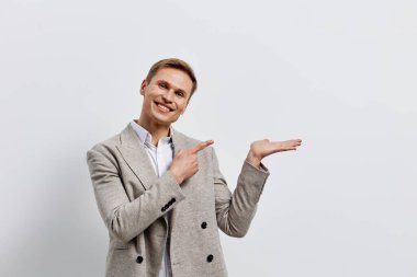 Gülümseyen adam beyaz arka planda izole edilmiş günlük ceket giyen açık el hareketi yapıyor. Bilgisayarlı ve iletişim konseptiyle dijital göçebe yaşam tarzında çalışan genç beyaz bir adam. modern