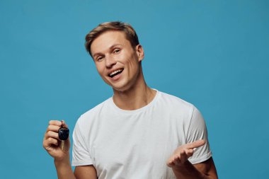 Kafkasyalı mutlu genç adam akıllı anahtarlığını tut mavi arka planda beyaz tişört giy yakın plan portre akıllı ev teknolojisi ve otomasyon konsepti dijital yaşam tarzı