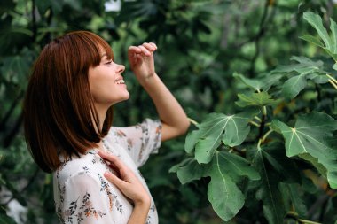 Huzurlu bir ortamda yükselen ağaçtaki canlı yeşil yapraklara bakan bir kadın.