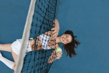 Neşeli bayan tenisçi, spor temalı içerik için mükemmel enerjik ve enerjik bir atmosfer sergileyerek sahada eğleniyor.