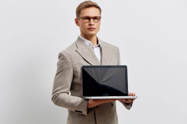 Akıllı takım elbiseli, gözlüklü, beyaz arka planda izole edilmiş, boş bir laptop ekranı sunan özgüvenli bir adam. Şirket, profesyonel, teknoloji, işyeri, iş dünyası, iletişim kavramı