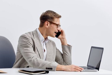 Çağdaş ofis ortamında masa başında otururken resmi giyinmiş iş adamı, yanında iş materyalleri, odaklanmış ve profesyonel ruh hali, modern