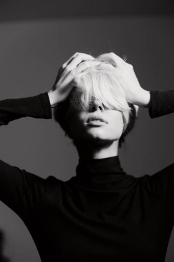 Düşünceli genç bir kadın iki eliyle başını tutuyor, derin duyguları canlandırıyor. Monokrom ayarı onun özelliklerini ve kıyafetlerini vurguluyor..