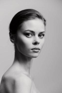 Düşünceli bakışlarını ve zarif duruşunu vurgulayan çarpıcı siyah beyaz bir genç kadın portresi. Tarafsız arka plan onun özelliklerini tamamlıyor, zamansız bir görünüm yaratıyor..