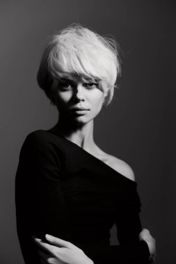 Minimalist görünümlü şık bir bayan model, omuz üstü kapalı siyah bir bluz giyiyor, güç ve kendine güvenini gösteriyor. Portre fotoğrafçılığı.